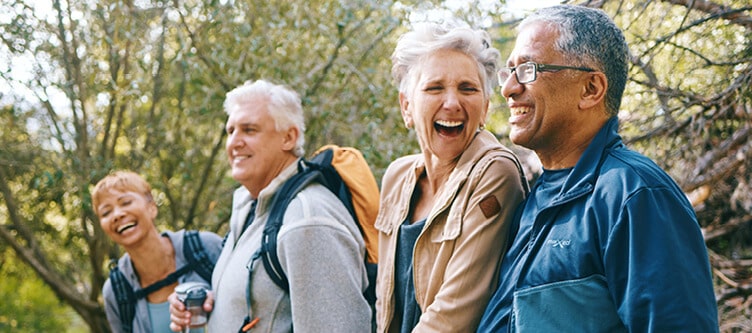 4 friends laughing while hiking through the woods